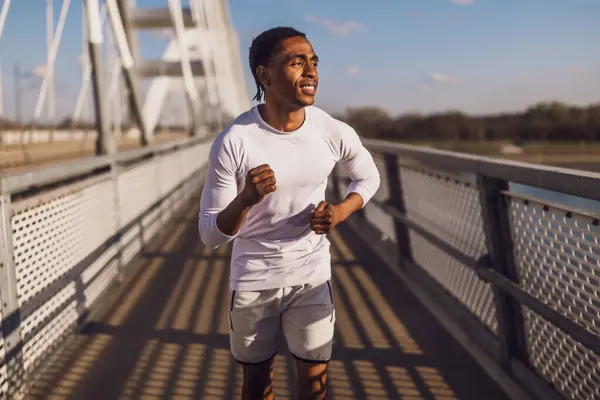 アフリカ系アメリカ人の若者が街の橋の上をジョギングしている ストック画像