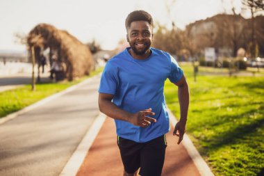 Genç Afro-Amerikalı adam şehirde koşuyor..