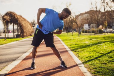 Genç Afro-Amerikan bir adam şehirde egzersiz yapıyor. Vücudunu esnetiyor..