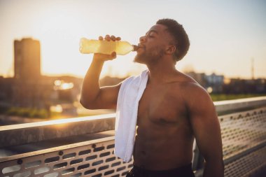 Koşu yaptıktan sonra dinlenen ve su içen Afrikalı Amerikalı genç bir adamın portresi..