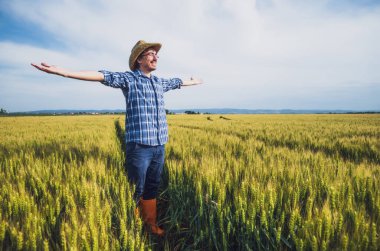 Buğday tarlasında mutlu bir çiftçi. Ekinlerden memnun..