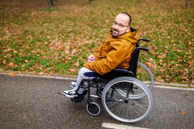 Parkta tekerlekli sandalyedeki felçli adamın mutlu portresi..