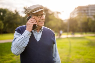 Güneşli bir günde parkta mutlu bir son sınıf öğrencisinin portresi. Cep telefonuyla konuşuyor..
