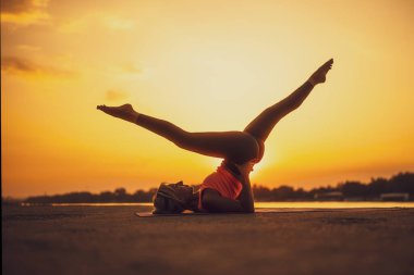 Gün batımında pilates yapan bir kadın. Makas egzersizi.. 