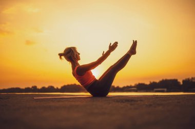 Gün batımında pilates uygulayan kadın. Teaser egzersiz.