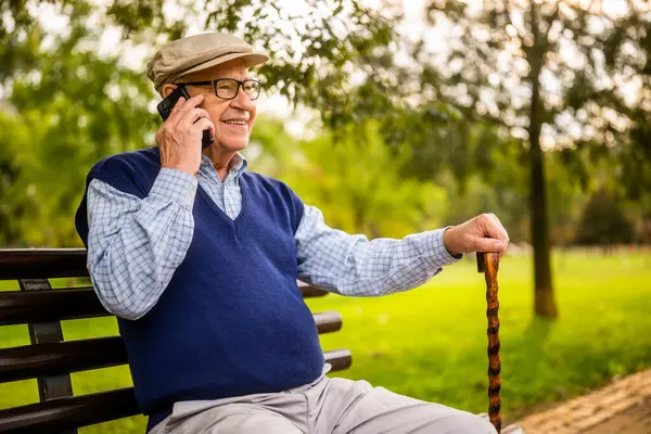 Park 'taki mutlu son sınıf öğrencisinin portresi. Bankta oturuyor ve telefonla konuşuyor..