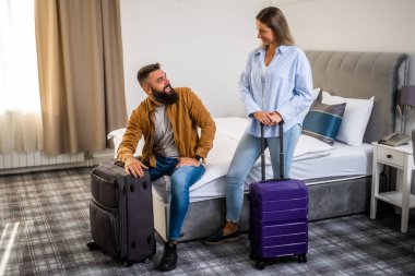 Genç mutlu çift tatilde. Turistler bavullarıyla otel odasına geldiler..