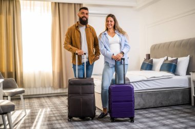 Genç mutlu çift tatilde. Turistler bavullarıyla otel odasına geldiler..