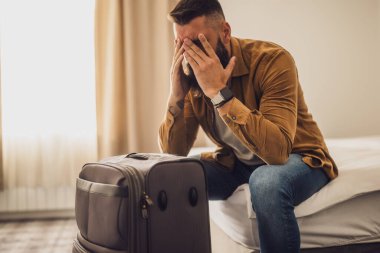 Turist bavuluyla otel odasına geldi. Seyahat etmekten yoruldu ve dinlenmeye ihtiyacı var..