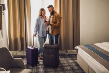 Genç mutlu çift tatilde. Turistler bavullarıyla otel odasına geldiler..