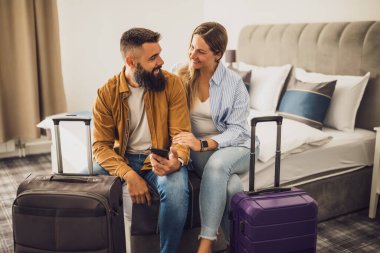 Genç mutlu çift tatilde. Turistler bavullarıyla otel odasına geldiler..