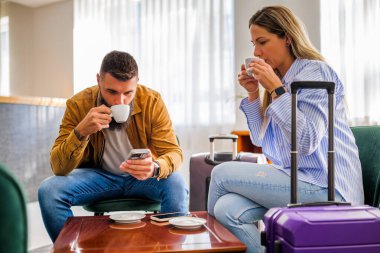 Genç çift tatile çıkıyor. Gecikmeli uçuş nedeniyle havaalanı kafesinde oturan turistler.