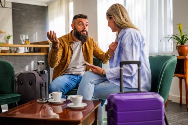 Genç çift tatile çıkıyor. Gecikmeli uçuş nedeniyle havaalanı kafesinde oturan turistler.