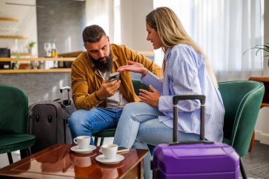 Genç çift tatile çıkıyor. Gecikmeli uçuş nedeniyle havaalanı kafesinde oturan turistler.