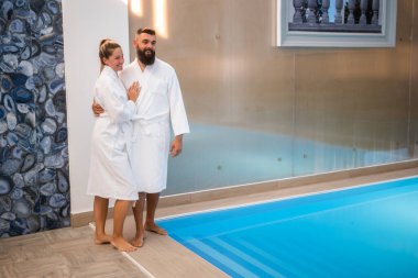 Genç mutlu çift yüzme havuzunun yanındaki spa merkezinde eğleniyor. Erkek ve kadın tatilde..