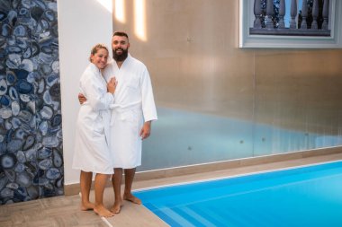 Genç mutlu çift yüzme havuzunun yanındaki spa merkezinde eğleniyor. Erkek ve kadın tatilde..