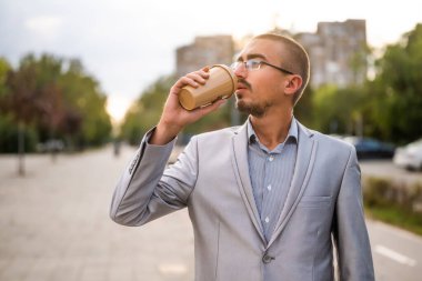 Sokakta durup kahve içen genç işadamının portresi..