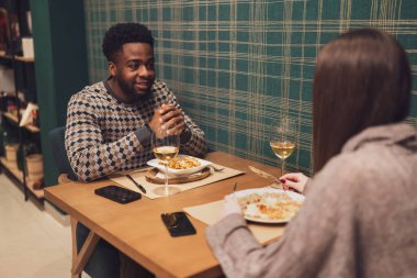 İki arkadaş restoranda akşam yemeği yiyorlar. Oturuyorlar, konuşuyorlar ve birlikte vakit geçiriyorlar..