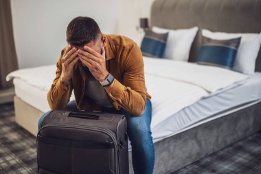 Turist bavuluyla otel odasına geldi. Seyahat etmekten yoruldu ve dinlenmeye ihtiyacı var..