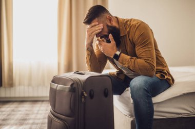 Turist bavuluyla otel odasına geldi. Seyahat etmekten yoruldu ve dinlenmeye ihtiyacı var..
