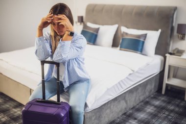 Turist bavuluyla otel odasına geldi. Seyahat etmekten yoruldu ve dinlenmeye ihtiyacı var..