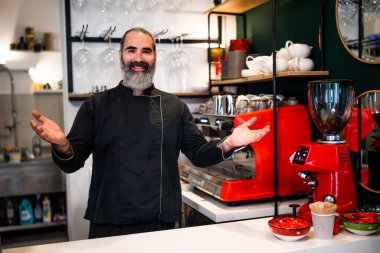 Restoranda çalışan siyah önlüklü profesyonel bir barista. Barında kahve yapan mutlu barmenlerin portresi..