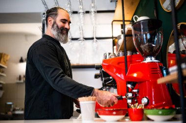 Restoranda çalışan siyah önlüklü profesyonel bir barista. Barında kahve yapan mutlu barmenlerin portresi..