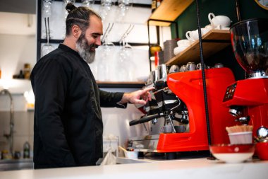 Restoranda çalışan siyah önlüklü profesyonel bir barista. Barında kahve yapan mutlu barmenlerin portresi..