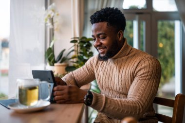 Çevrimiçi iletişim kurmak için dijital tablet kullanıyor. Barda oturuyor ve internetten iletişim kuruyor..