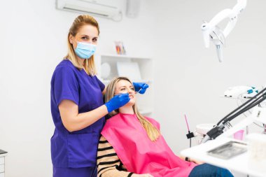 Diş hekiminde bir hastayı muayene eden bir dişçi. İşte mutlu bir dişçi, kameraya bakıyor..