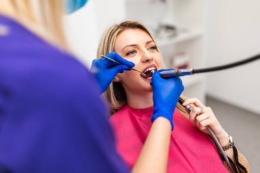 Hastanın dişlerini delen dişçi. Dişlerini yaptıran genç bir kadın..