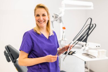 Diş hekiminin ofisinde mutlu bir dişçinin portresi. Kendine güvenen yetişkin bir kadın dişçi kliniğinde çalışıyor..