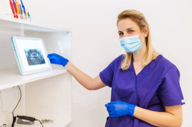 Dişçi çene ve dişlerin x-ray resmini inceliyor.