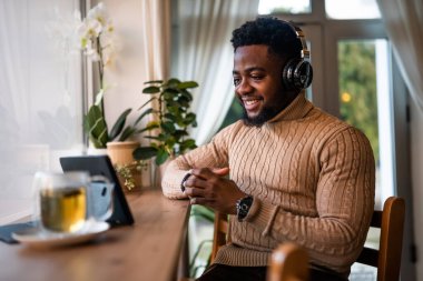 Çevrimiçi iletişim kurmak için dijital tablet kullanıyor. Barda oturuyor ve video görüşmesi yapıyor..
