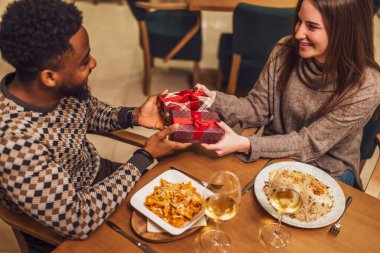 İki arkadaş restoranda akşam yemeği yiyorlar. Birbirlerine hediye veriyorlar..