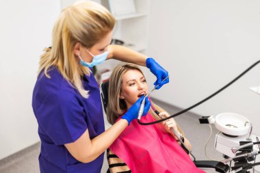 Hastanın dişlerini delen dişçi. Dişlerini yaptıran genç bir kadın..