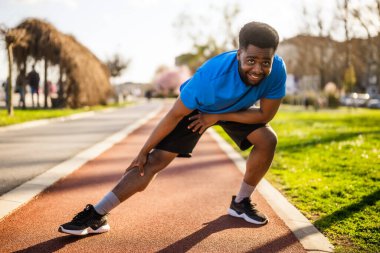 Genç Afro-Amerikan bir adam şehirde egzersiz yapıyor. Vücudunu esnetiyor..