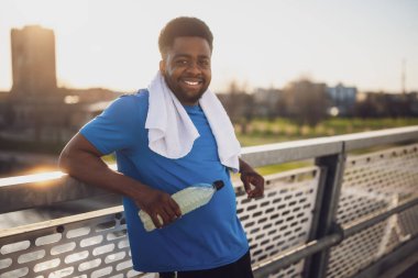 Koşu yaptıktan sonra dinlenen ve su içen Afrikalı Amerikalı genç bir adamın portresi..