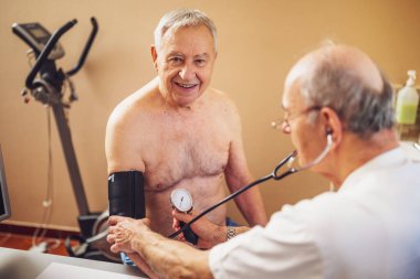 Hastanın kardiyologda muayenesi var. Doktor hastasına kan basıncını ölçüyor..