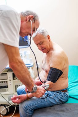 Hastanın kardiyologda muayenesi var. Doktor hastasına kan basıncını ölçüyor..