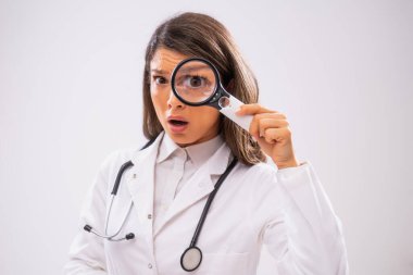 Büyüteçle bakan endişeli kadın doktorun stüdyo fotoğrafı..