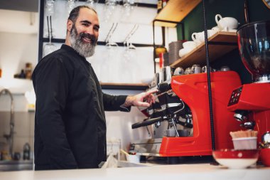 Restoranda çalışan siyah önlüklü profesyonel bir barista. Barında kahve yapan mutlu barmenlerin portresi..