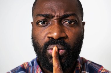 Sessiz kalmak isteyen kızgın ve ciddi siyahi bir adamın portresi..