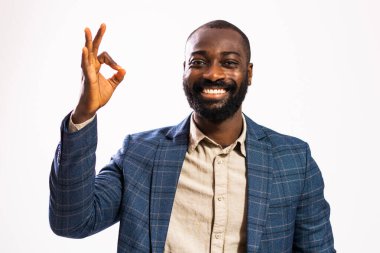 Mutlu ve başarılı bir iş adamının portresi. Siyah takım elbiseli adam kameraya bakıyor ve tamam işareti gösteriyor..