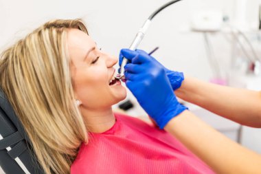 Hastanın dişlerini delen dişçi. Dişlerini yaptıran genç bir kadın. Kapat..