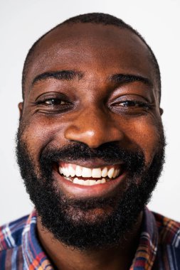 Mutlu ve neşeli siyahi bir adamın portresini yakından çek. Yetişkin adam kameraya bakıyor ve gülüyor..