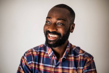 Kapalı tişörtlü mutlu siyahi adamın portresi gülümsüyor ve başka tarafa bakıyor..