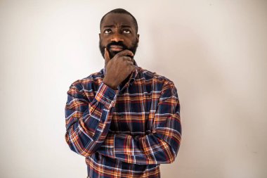 Rahat gömlekli dalgın siyah adam duvarda yatıyor, yukarı bakıyor ve düşünüyor..