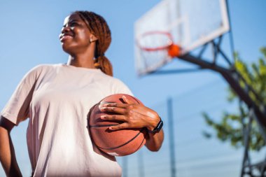 Genç bir kadın sabah spor salonunda tek başına basketbol oynuyor. Topa seçmeli odaklan.