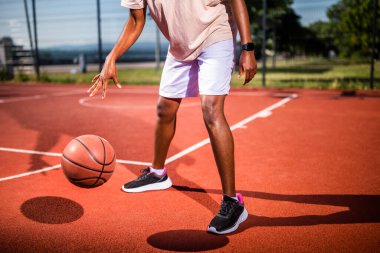 Genç siyahi kadın sabahları spor salonunda tek başına basketbol oynuyor. O, topu sürüyor..